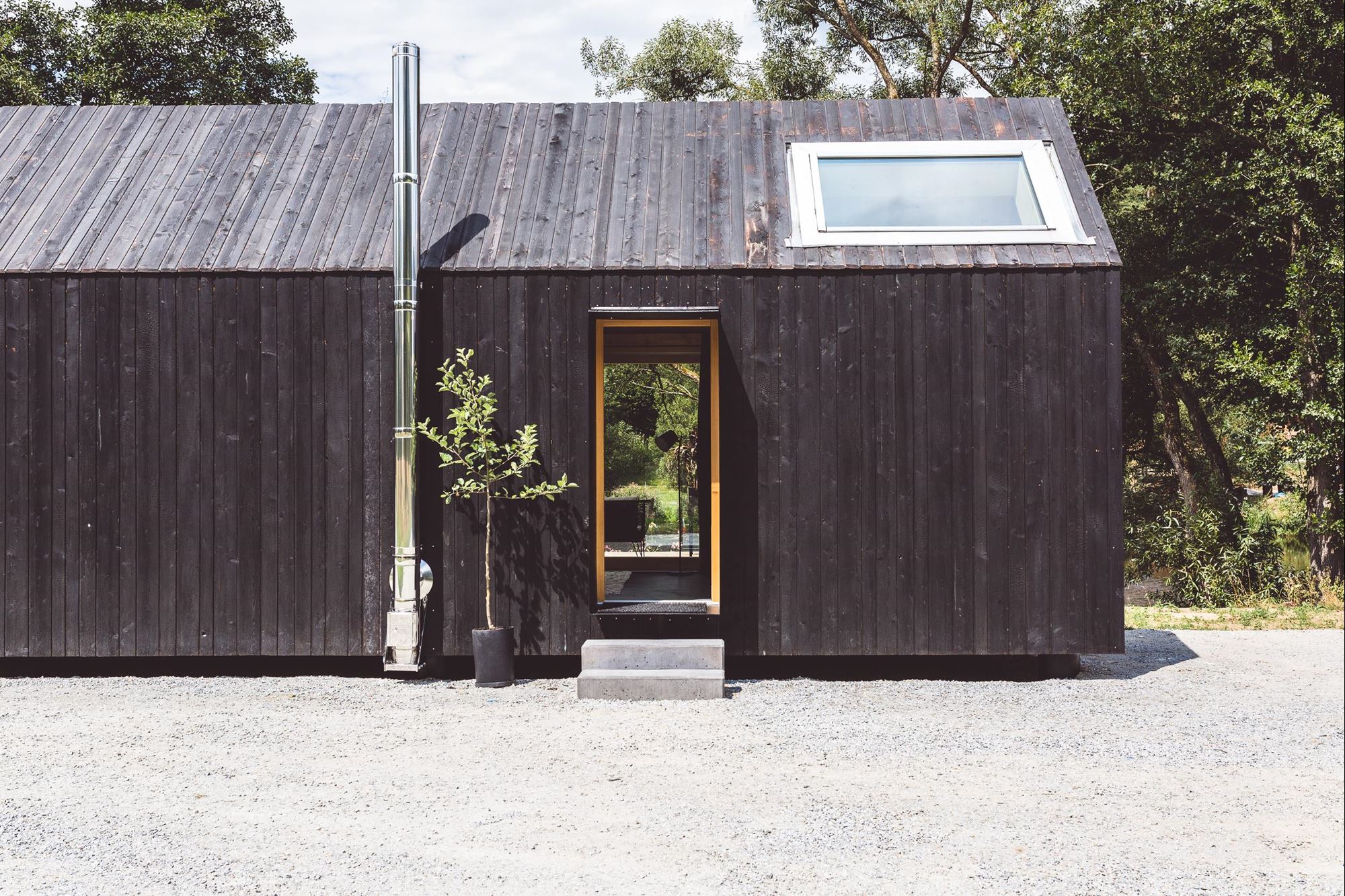 ein kleines schwarzes Gebäude mit einem Schornstein