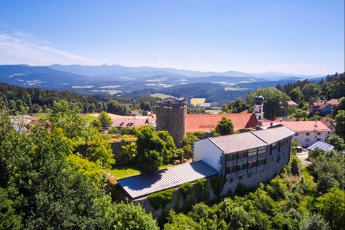 ein Gebäude auf einem Hügel mit Bäumen und Bergen im Hintergrund