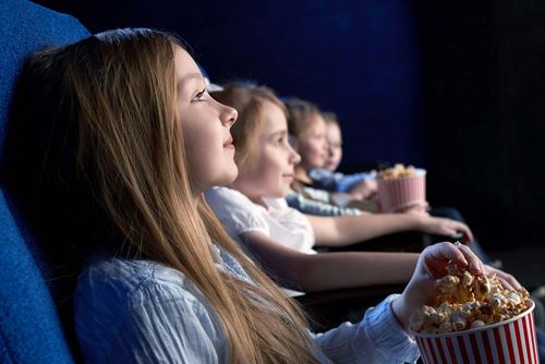 Mehrere Kinder sitzen in einem Kinosaal und wenden sich aufmerksam der Leinwand zu
